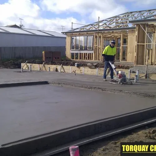 Skilled tradespeople working on the installation of an exposed aggregate driveway, showcasing expert craftsmanship and tools